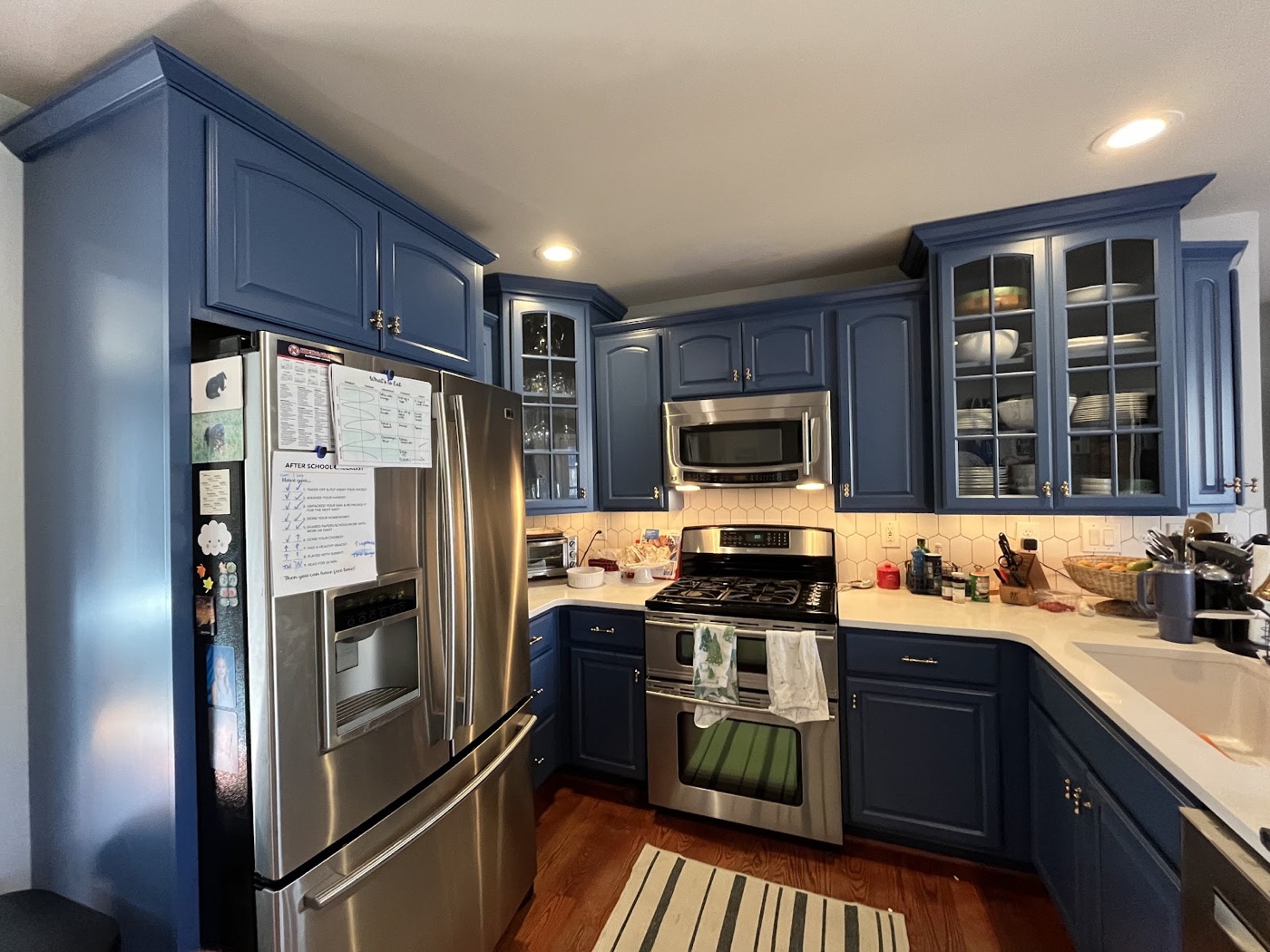 Kitchen with deep navy cabinets repainted by Cris P Painting