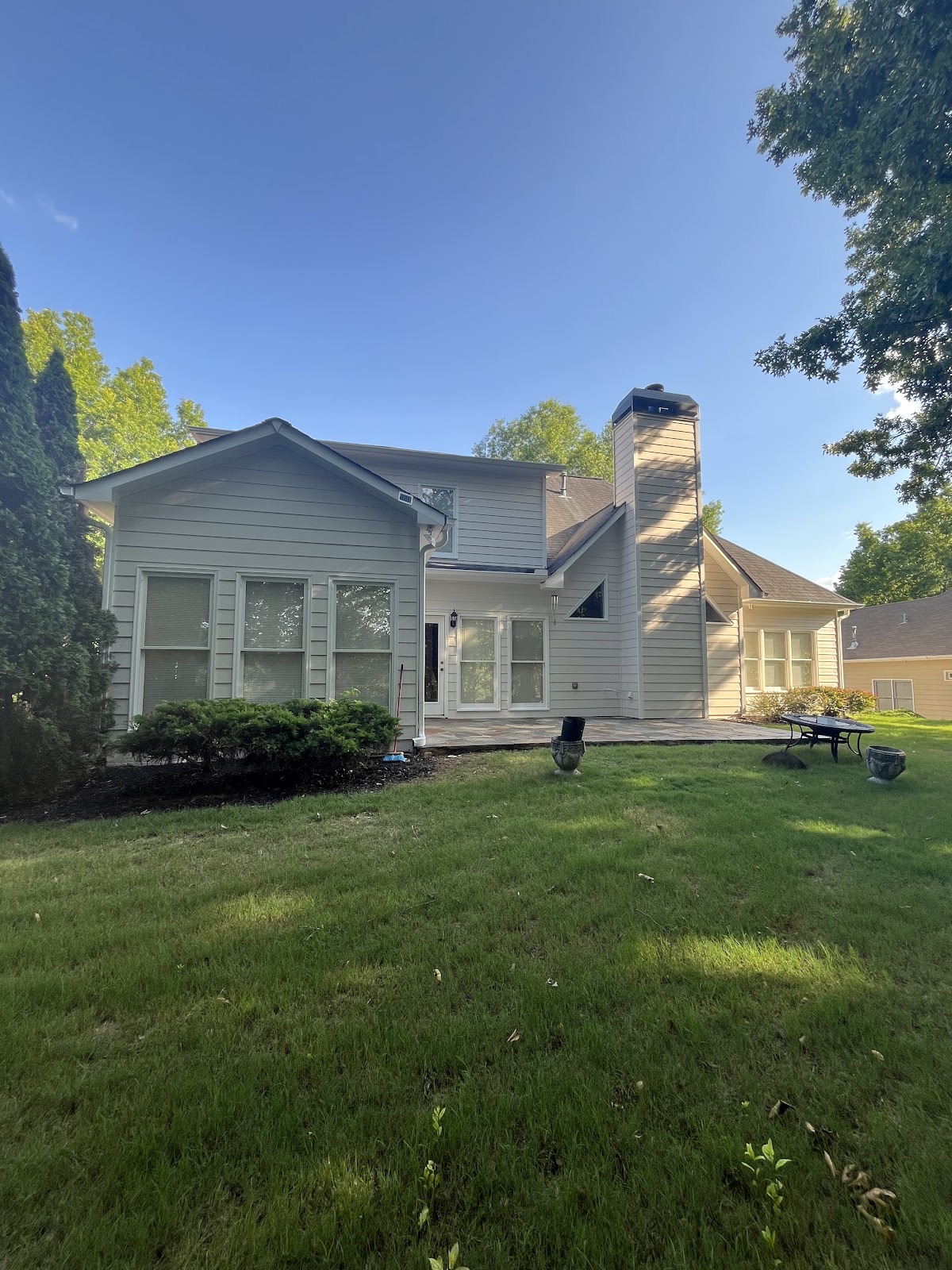 Two-story home with freshly painted cream siding and a sunny backyard