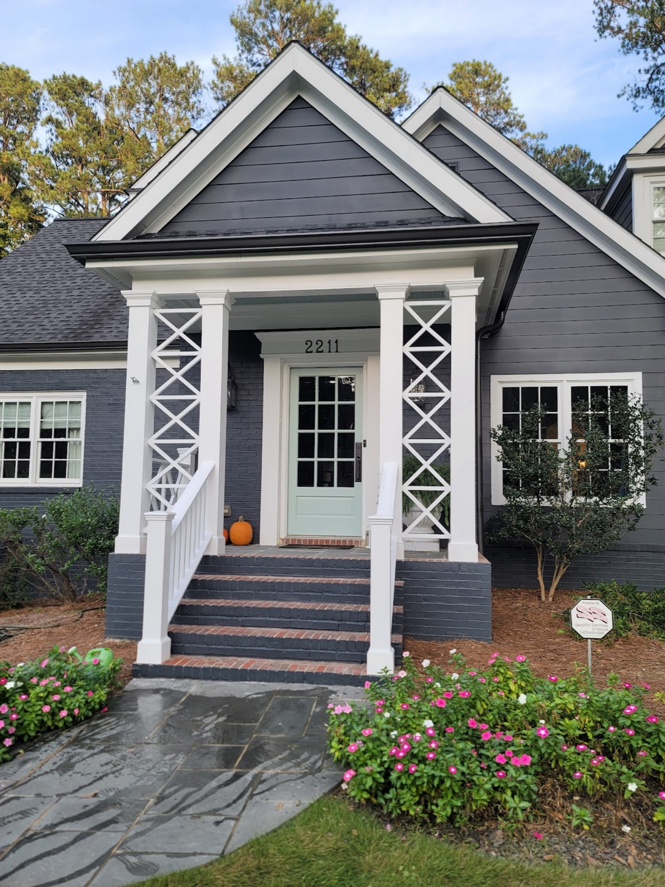 Navy craftsman cottage with white columns and a sage-painted front door, painted by Cris P Painting